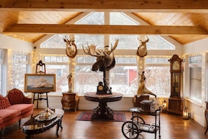 A cozy room with wooden beams, a large window, and a fireplace.