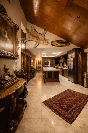 A spacious kitchen with a marble floor, wooden cabinets, and a central island.