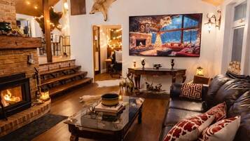 A cozy living room with a fireplace, leather sofa, and a large television.