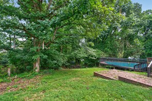 A backyard with a swimming pool, a wooden deck, and a brick patio. - Modern Furnished Home Near CLT Airport (Charlotte)