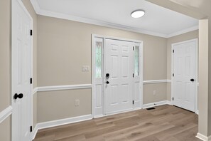 A hallway with two white doors, beige walls, and wooden flooring. - Modern Furnished Home Near CLT Airport (Charlotte)