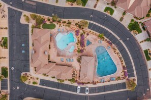 Eine Vogelperspektive auf ein Wohngebiet mit zwei Schwimmbecken, einem Parkplatz und umliegender Bepflanzung.