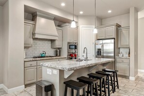 A modern kitchen with a central island, stainless steel appliances, and bar stools. - Coral Ridge 1998, Game Console, Resort Pool, Golf Nearby, and Golf Nearby! (St. George)
