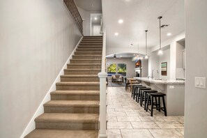 Eine Treppe führt zu einem Essbereich, im Hintergrund ist eine Küche zu sehen.