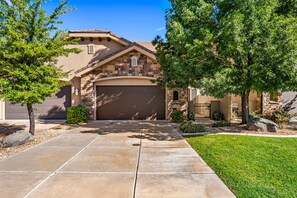 A residential house with a stone facade, a garage, and a well-maintained lawn. - Coral Ridge 1998, Game Console, Resort Pool, Golf Nearby, and Golf Nearby! (St. George)