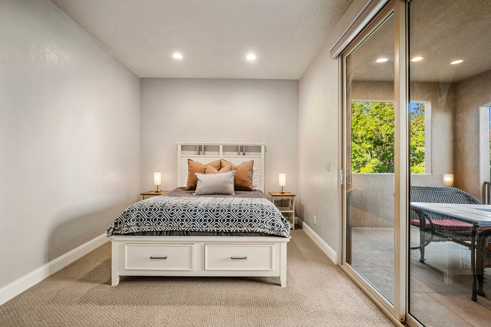 A bedroom with a bed, bedside tables, and a sliding glass door leading to an outdoor area.
