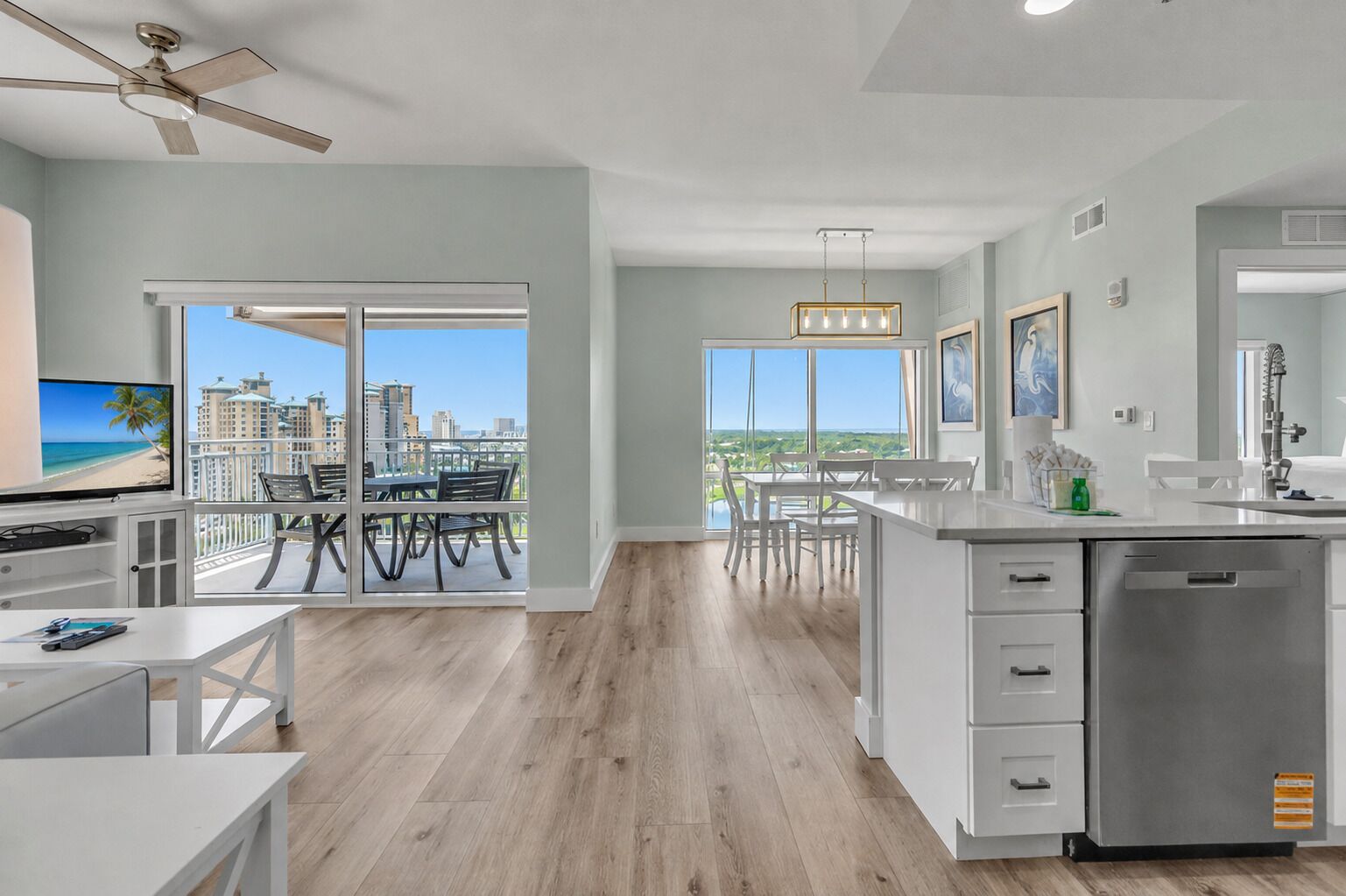 A modern kitchen with a large island, a dining area with a view, and a balcony with a cityscape view.