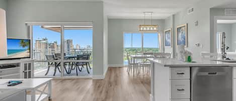 Una cocina moderna con una isla grande, un comedor con vistas y un balcón con vista a la ciudad.