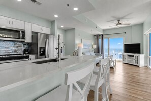 Una cocina moderna con una isla central, muebles blancos y electrodomésticos de acero inoxidable.