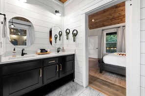 A modern bathroom with a black vanity, white tiled walls, and a wooden ceiling. - Private & Romantic | Hot Tub, ATV Trails access (Broken Bow)