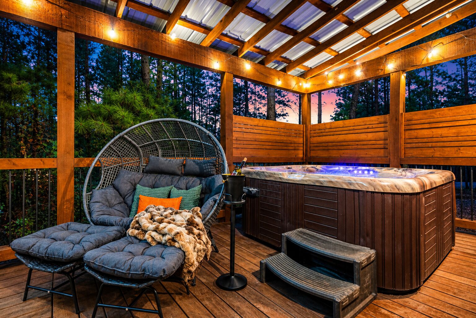 Un área de hidromasaje al aire libre con una terraza de madera, una silla colgante y un banco acolchado.