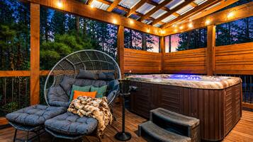 Un área de hidromasaje al aire libre con una terraza de madera, una silla colgante y un banco acolchado.