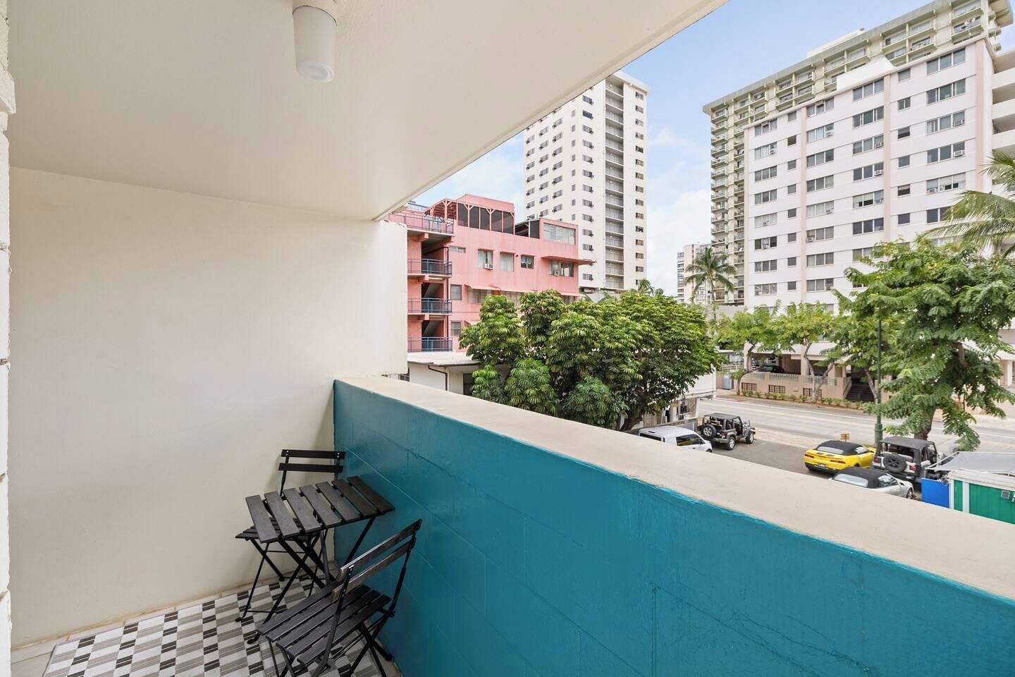 Ein Balkon mit kariertem Boden, einem Tisch und Stühlen.