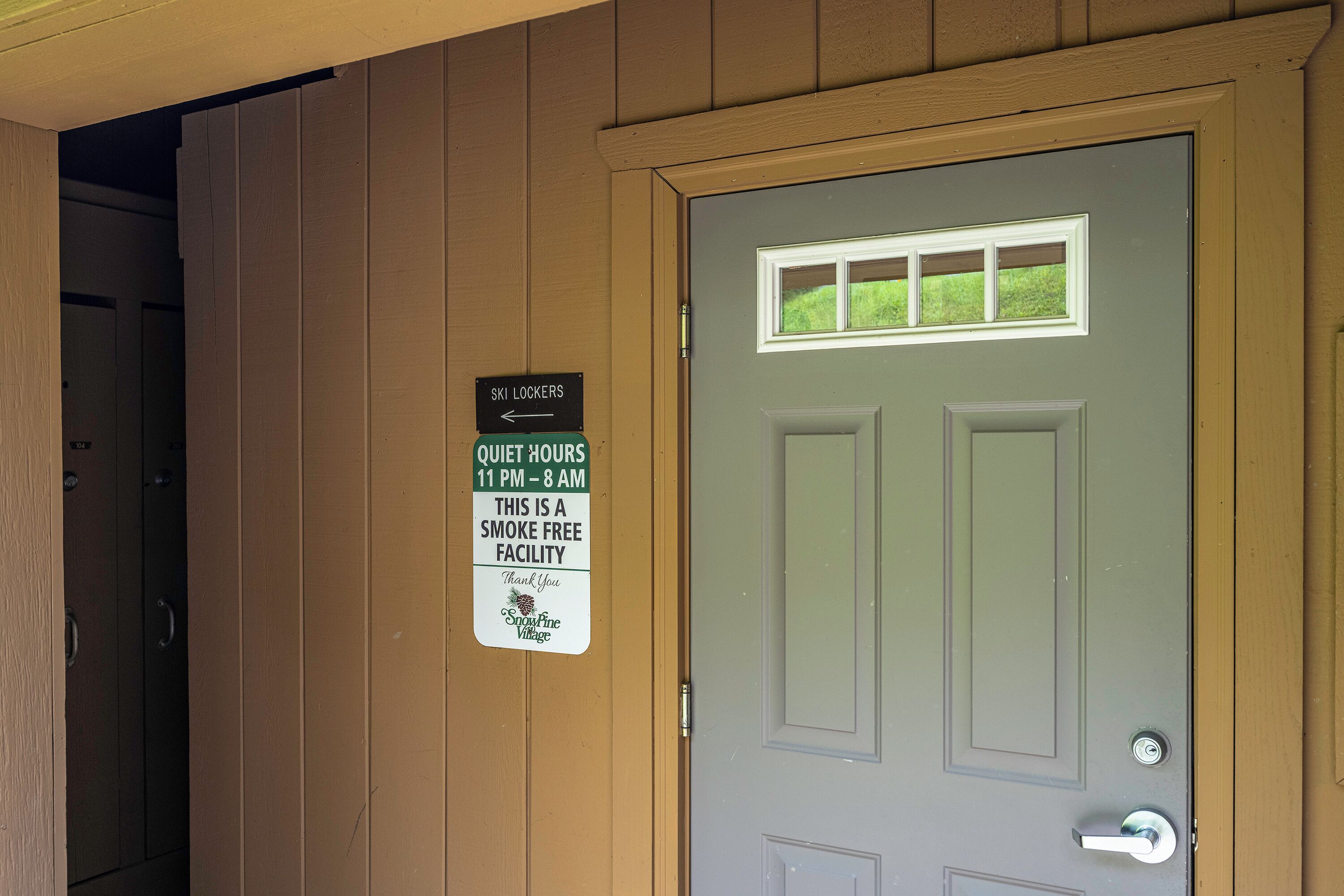 A door with a sign indicating quiet hours and a smoke-free facility.