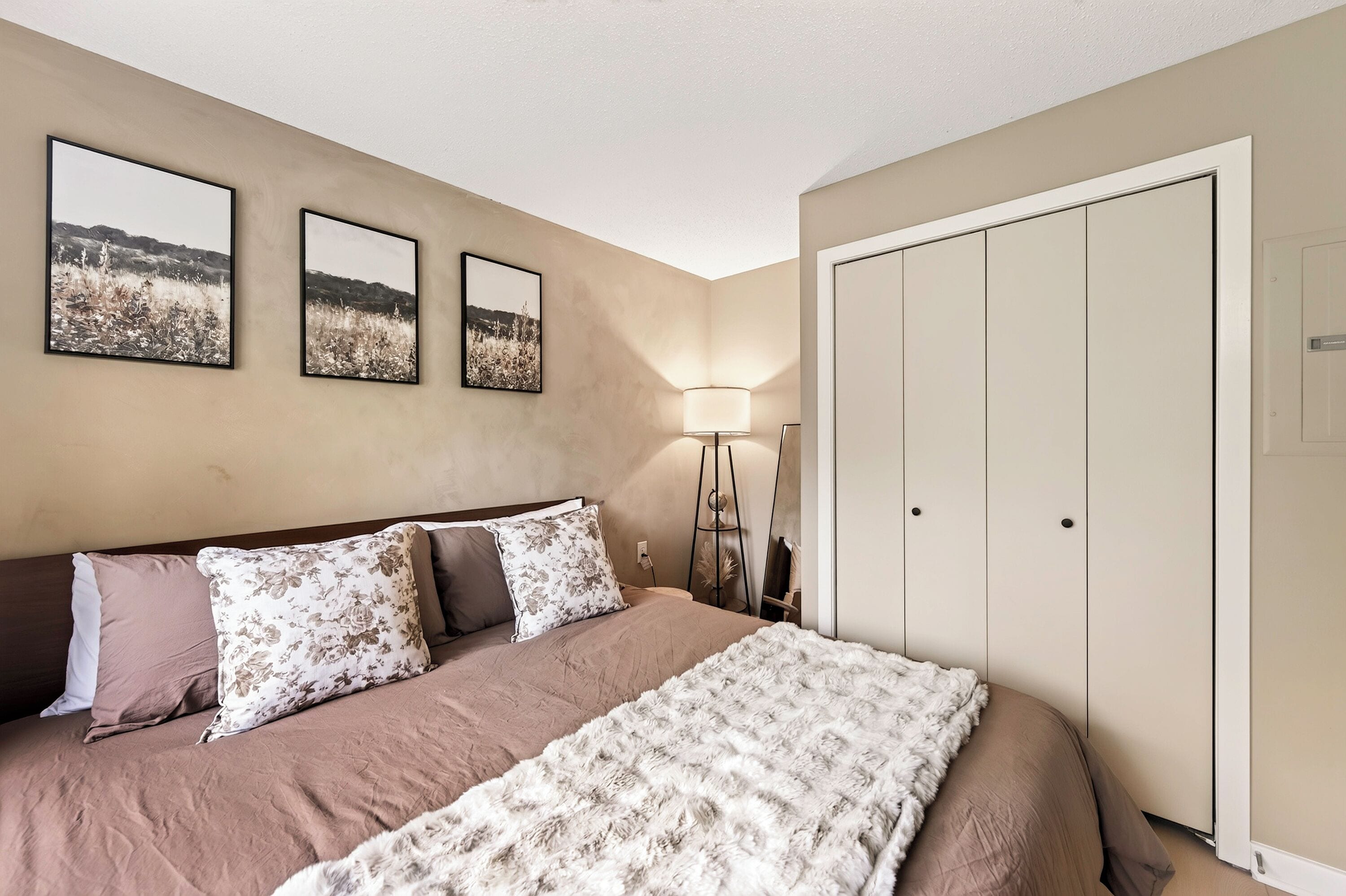 A bedroom with a bed, a nightstand, a lamp, and a wardrobe.