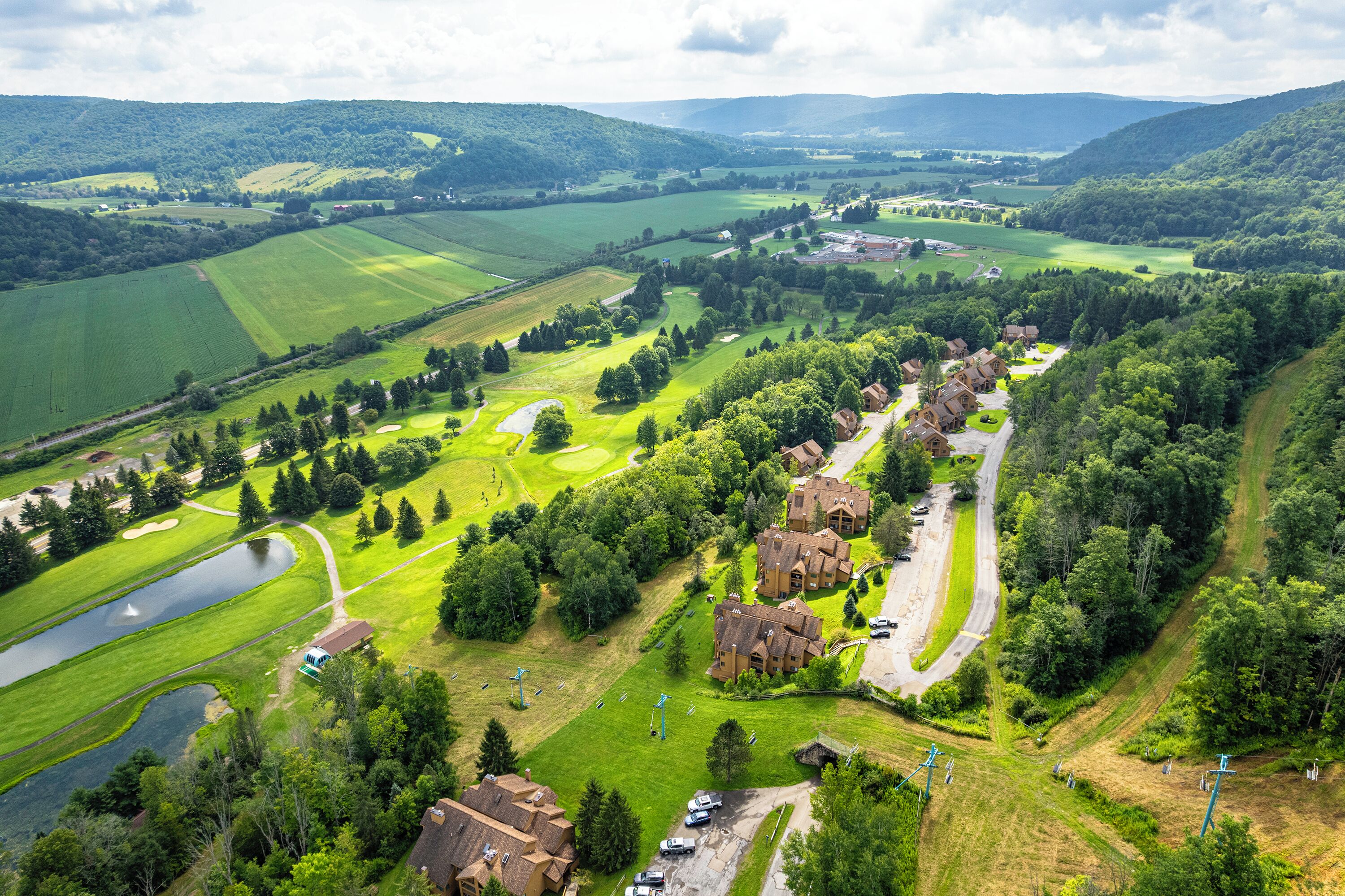 Ein Golfplatz mit Clubhaus, Teich und umliegenden Grünflächen.
