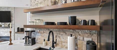 Una cocina con pileta integrada, cafetera y extractor.