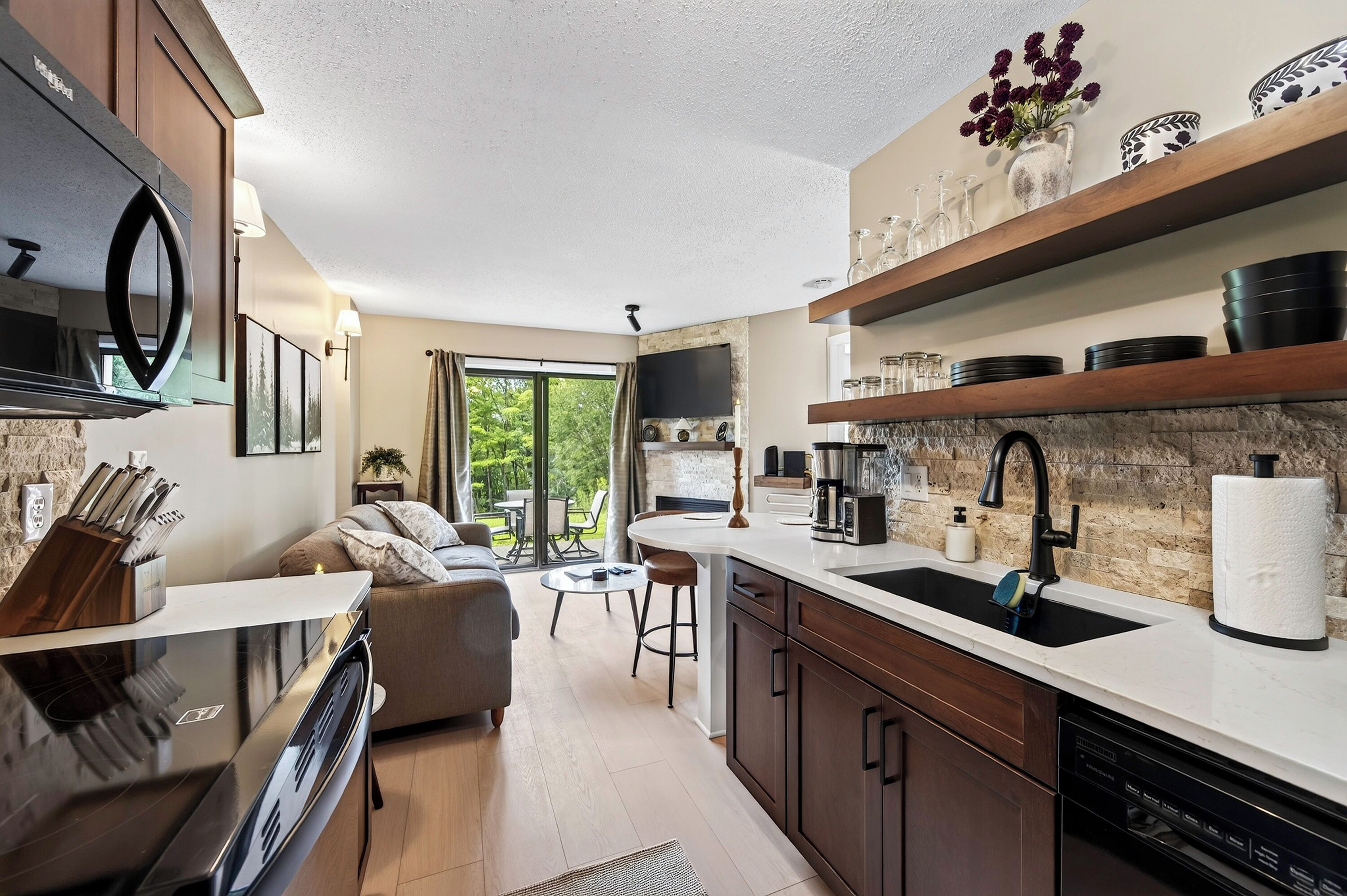 A modern kitchen with a built-in oven, a coffee machine, and a sink with a paper towel holder.