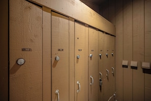 A row of wooden lockers with numbered doors, each equipped with a lock and a handle.