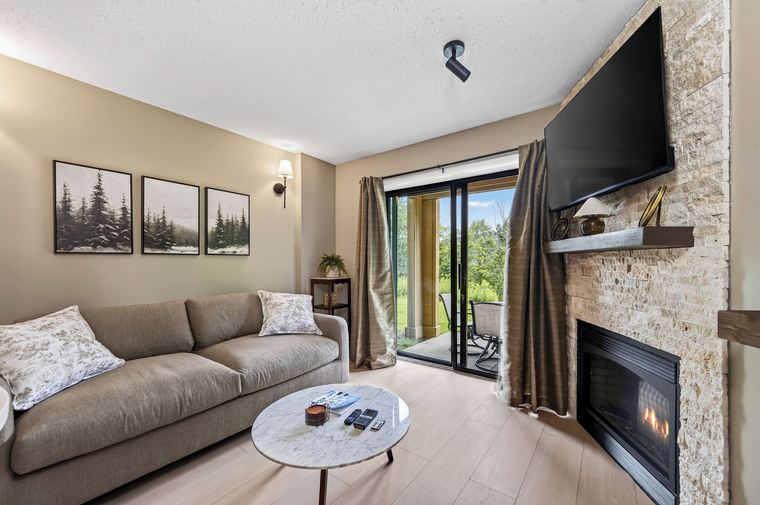 Un salon comprenant un canapé, une table basse, une cheminée et un téléviseur fixé au mur.