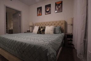 A bedroom with a tufted headboard, a patterned bedspread, and three wall-mounted artworks. - Cozy 1-bedroom apartment in gorgeous The Woodlands with AC (The Woodlands)