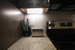 A kitchen with a toaster, a stove, and a knife block. - Cozy 1-bedroom apartment in gorgeous The Woodlands with AC (The Woodlands)
