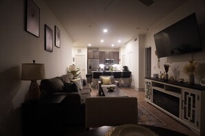 A modern living room with a sofa, coffee table, and a flat-screen TV mounted on the wall. - Cozy 1-bedroom apartment in gorgeous The Woodlands with AC (The Woodlands)