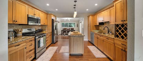 A modern kitchen with wooden cabinets, stainless steel appliances, and a central island.