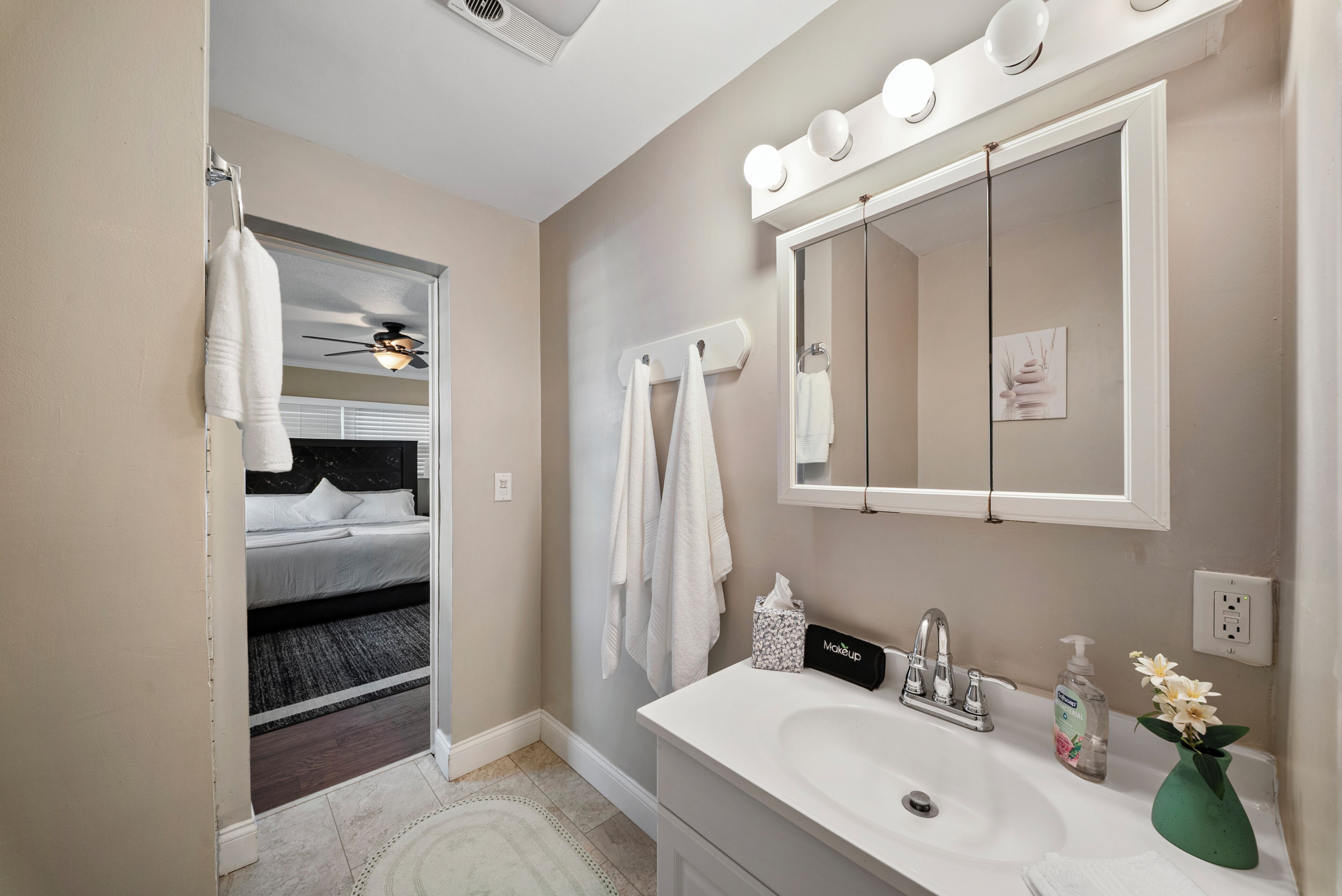 A hotel bathroom with a large mirror, a sink, a towel rack, and a shower area.