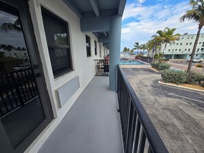 A building with a covered balcony, a pool, and palm trees in the background. - Free Parking Ocean Studio Full Kitchen (Hollywood)