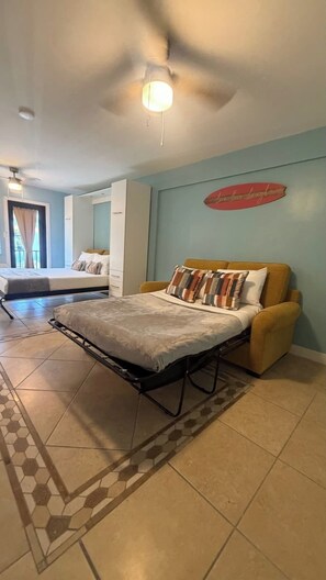 A bedroom with a bed, a sofa, a ceiling fan, and a wall with a decorative sign. - Free Parking Ocean Studio Full Kitchen (Hollywood)