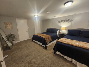 A hotel room with two beds, a nightstand, a lamp, a ceiling light, a door, and a plant. - En-Tice-ing 1 Bd Getaway Sandy Ut Mtns Ski & I-15 (Sandy)