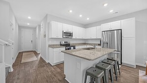 A modern kitchen with white cabinets, stainless steel appliances, and a granite countertop. - Enjoyable 4-bedroom house with AC in charming Little River (Little River)