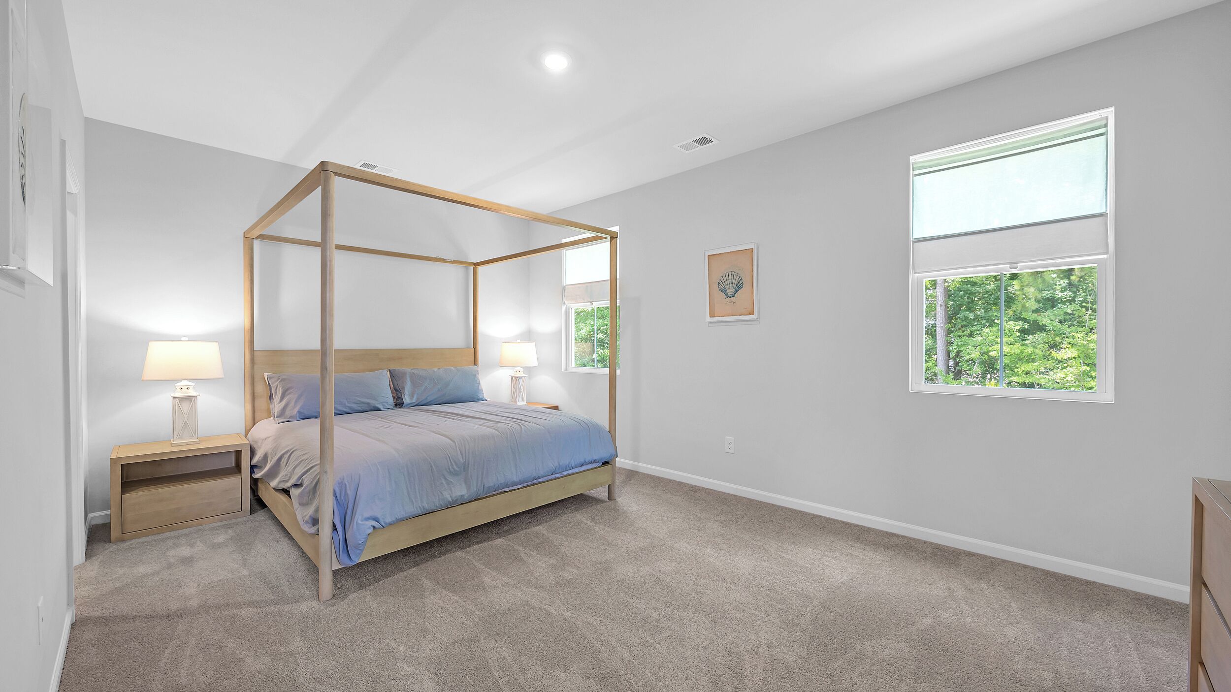 Un dormitorio con cama con dosel, dos mesitas de noche, un ventanal con vistas a la vegetación y una obra de arte colgada en la pared.