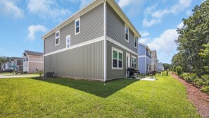 A modern two-story residential building with a well-maintained lawn and a patio area. - Enjoyable 4-bedroom house with AC in charming Little River (Little River)