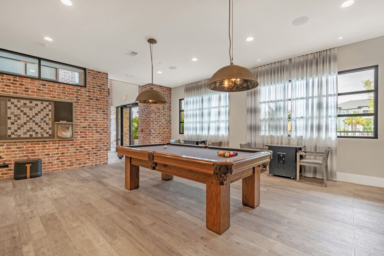 A spacious room with a pool table, a brick wall, and a billiards rack.
