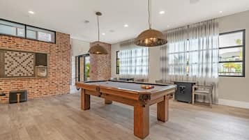 A spacious room with a pool table, a brick wall, and a billiards rack.