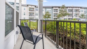 A balcony with a chair, a railing, and a view of multi-story residential buildings. - Luxury Retreat, Close to Disney (Winter Garden)
