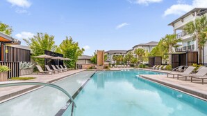 A swimming pool with lounge chairs and a brick structure in the center. - Luxury Retreat, Close to Disney (Winter Garden)