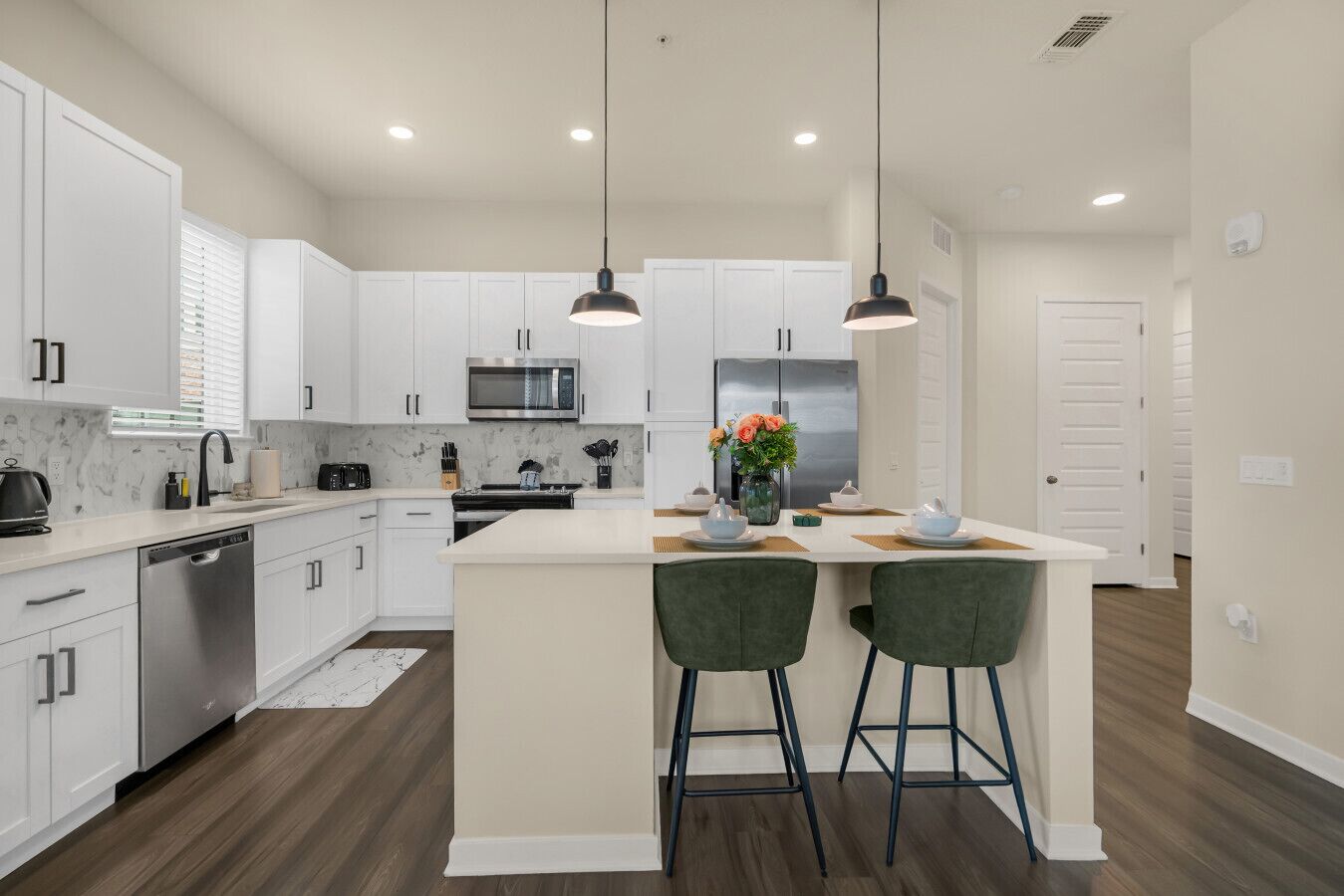 A modern kitchen with white cabinets, stainless steel appliances, and a central island with bar stools.
