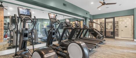 Ett gym med löpband, crosstrainers och en vägg full av speglar.