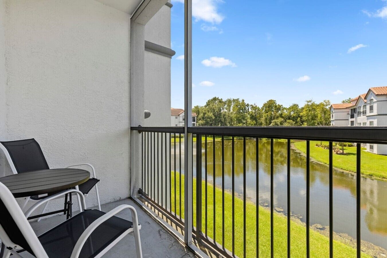 A balcony with a table and chairs, overlooking a body of water and buildings.