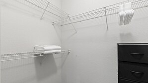 Ein Teil eines Raumes mit einem Wäscheständer aus Metall, einem schwarzen Hängeschrank und einer weißen Wand.