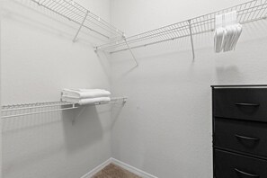 Ein Teil eines Raumes mit einem Wäscheständer aus Metall, einem schwarzen Hängeschrank und einer weißen Wand.
