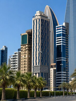 A modern urban skyline with high-rise buildings, including a prominent curved structure with signage. - Citadines Sharq Kuwait (Kuwait City)