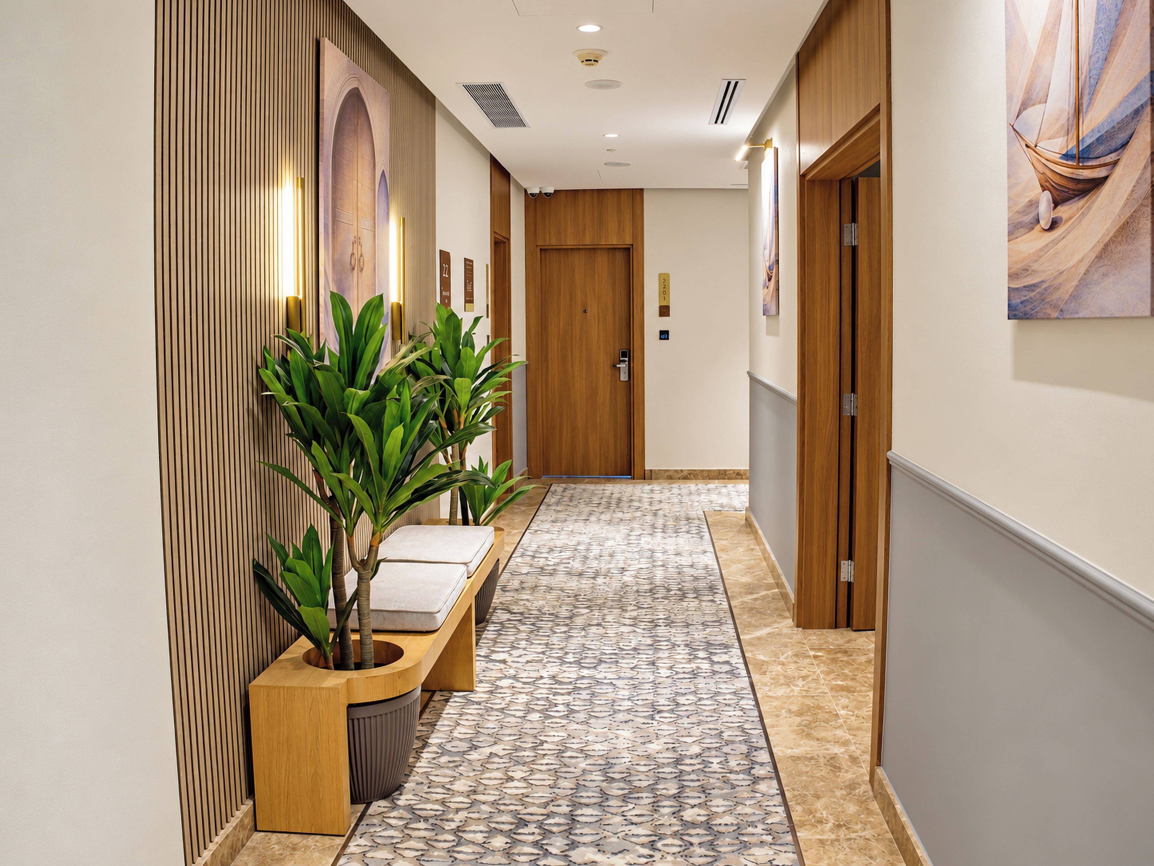 A hallway with a patterned floor, wooden paneling, a bench with a plant, and a door with a number sign.