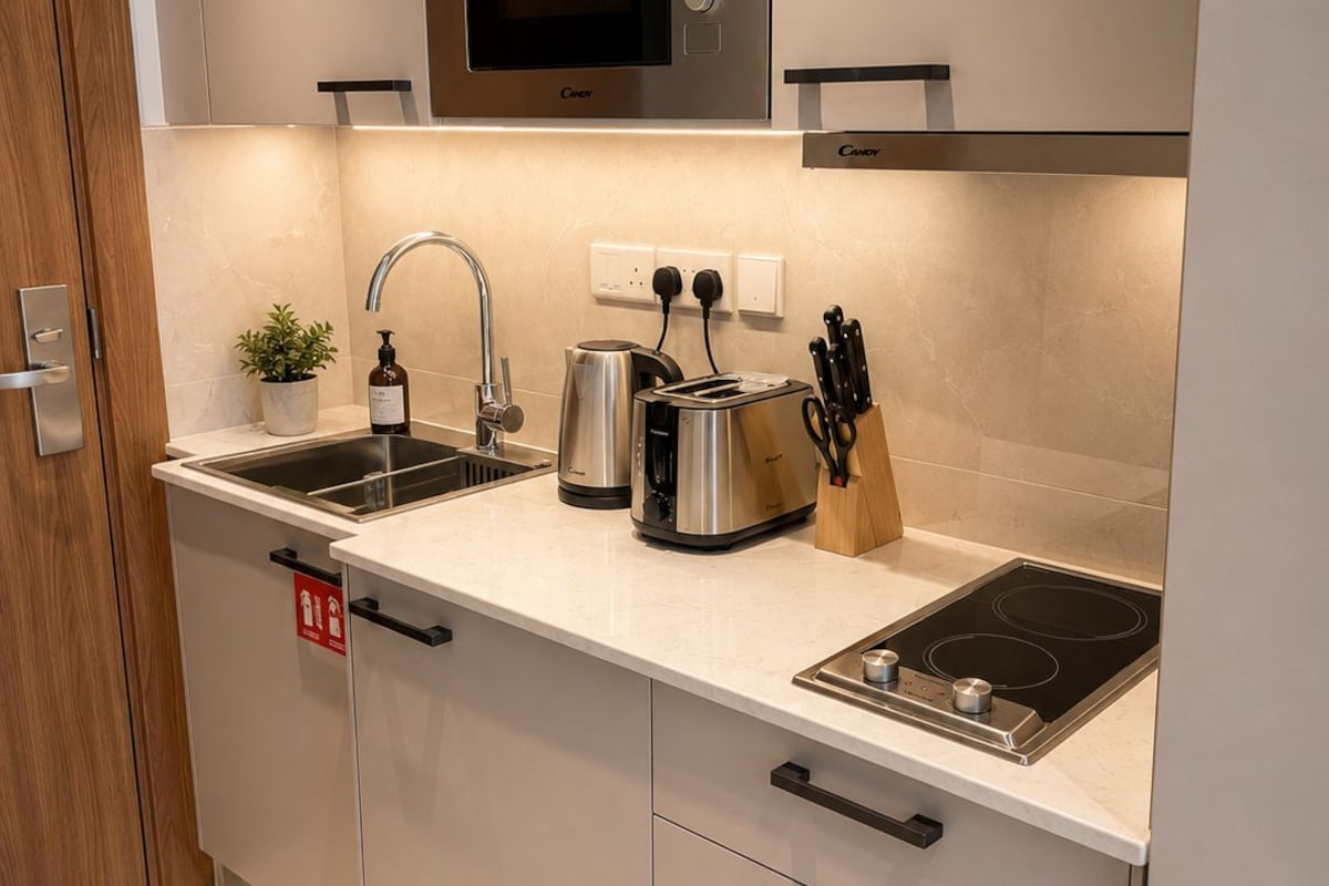 A modern kitchen with a built-in microwave, a kettle, a toaster, and a stove.