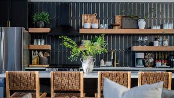 Una cocina moderna con una isla central, sillas de madera, una planta en maceta y utensilios de cocina en estantes.