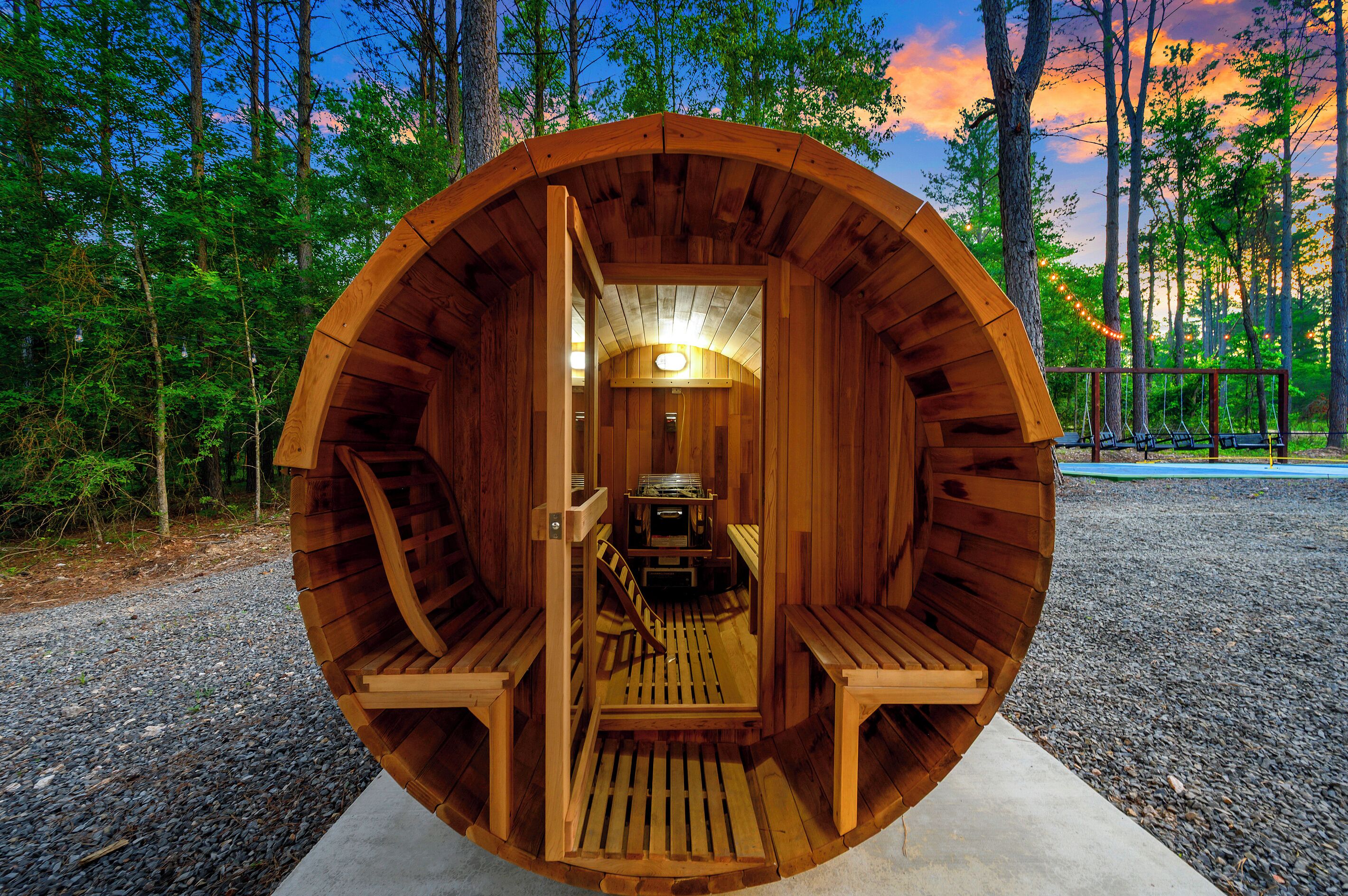 Una estructura de sauna de madera con bancos y una mesa, rodeada por un bosque.