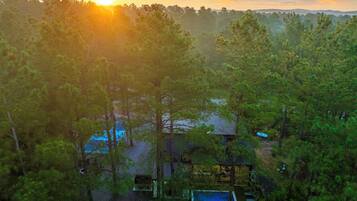 Una cabaña apartada rodeada de un bosque frondoso, con piscina visible y una pequeña terraza.